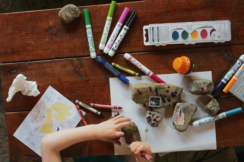 Mains d'enfant manipulant du matériel de création sur une table en bois